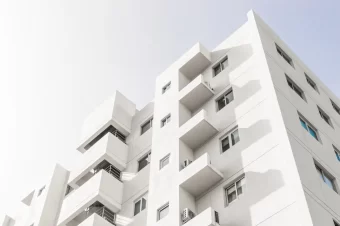 Foto de baixo ângulo da fachada de um edifício moderno branco sob um céu azul claro onde pode fazer locação de imóvel no airbnb.